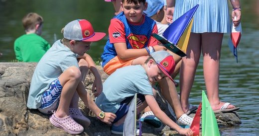 Children launching small sailboats at the Festival of Arts.