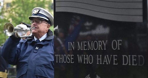John Collins plays taps beside a memorial stone.