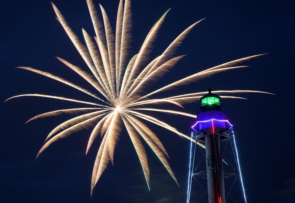 Fireworks burst beside the illuminated Marblehead Light.