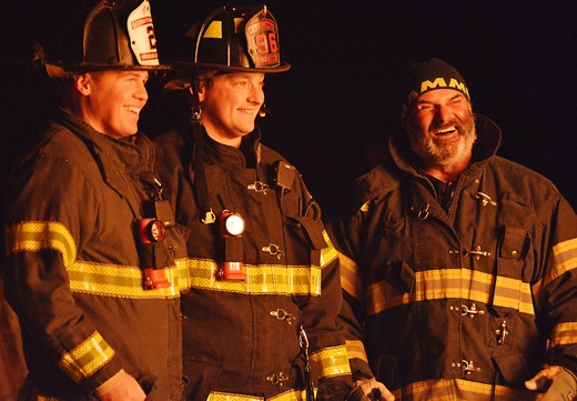 Three firefighters lit by the Epiphany bonfire.