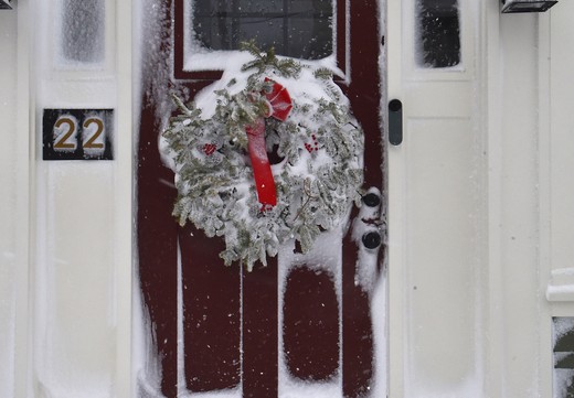 A wreath on a red door rimed with snow.